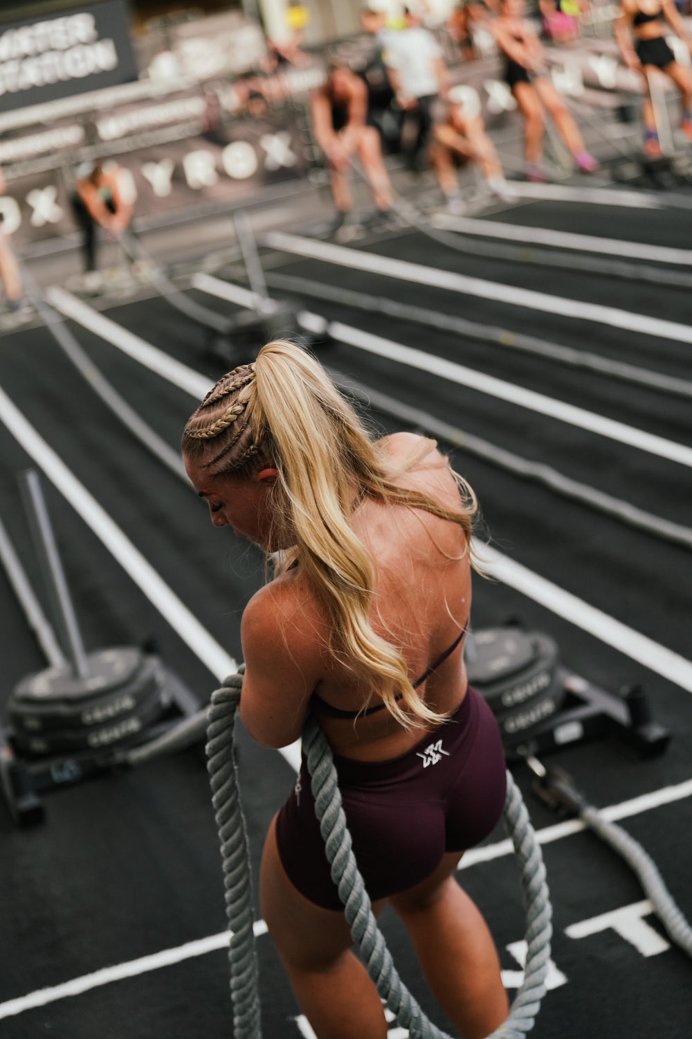Atlete trekt een touw op de HYROX-vloer